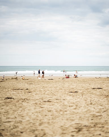 Wide sandy beach with scattered guests on a cloudy summer day