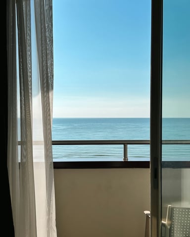 Ocean view through sheer curtains on a condo balcony