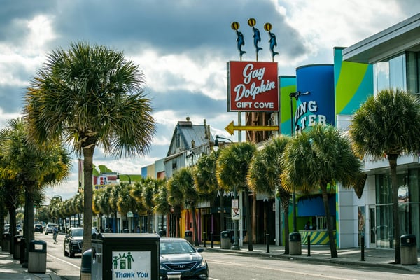 Palm-lined street in Myrtle Beach with shops and restaurants