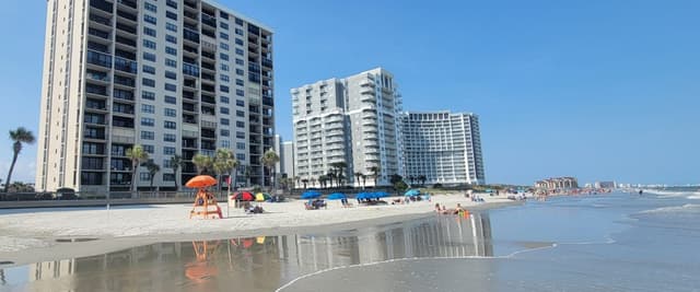 Beachfront high-rise condominiums with sandy beach, lifeguard stand, and ocean in foreground