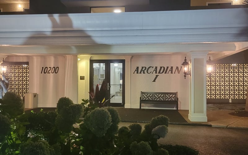 Illuminated mid-century modern storefront with address 10200 and Arcadian I signage, geometric lattice panels, and desert landscaping at night